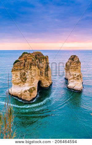 Beautiful sunset on Raouche, Pigeons' Rock. In Beirut, Lebanon.Sun and Stones are reflected in water.dense clouds in the sky.