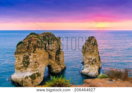 Beautiful sunset on Raouche, Pigeons' Rock. In Beirut, Lebanon.Sun and Stones are reflected in water.dense clouds in the sky.