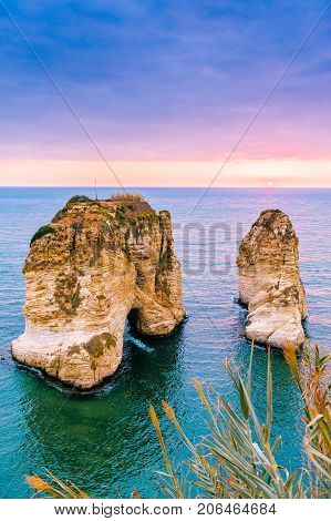 Beautiful sunset on Raouche, Pigeons' Rock. In Beirut, Lebanon.Sun and Stones are reflected in water.dense clouds in the sky.