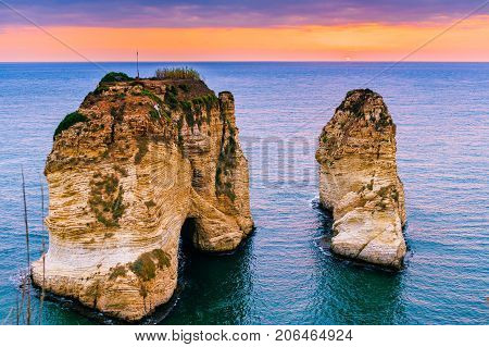 Beautiful sunset on Raouche, Pigeons' Rock. In Beirut, Lebanon.Sun and Stones are reflected in water.dense clouds in the sky.