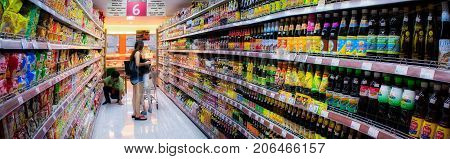 BANGKOK THAILAND - AUGUST 12: Unidentified shoppers shop in the soy sauce aisle in Foodland Supermarket as an unidentified store Keeper organizes inventories on August 12 2017 in Bangkok.