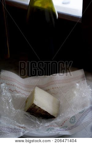 wedge of sardinian pecorinowith in background a bottle of red wine
