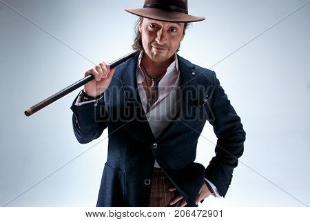 The mature bearded man in a suit and hat holding cane. Isolated on a gray studio background.