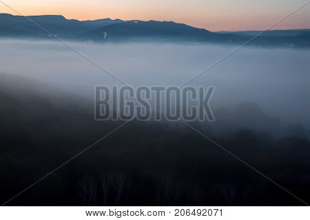 Fantastic landscape of foggy mountains at sunrise
