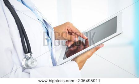 Woman doctor using tablet computer while standing straight in hospital.