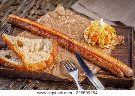 Long sausage grilled. with vegetable salad. Fast food in the restaurant. Delicious fried sausages. Grilled sausages from fresh meat.