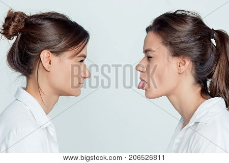 Studio profile portrait of young female twins sisters on gray