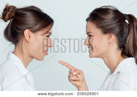 Studio profile portrait of young female twins sisters on gray