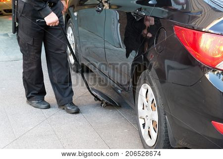 The guard examines the bottom of the car with a mirror