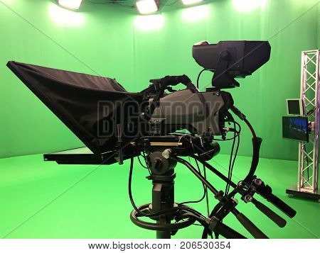 Modern empty green video recording and broadcasting studio with tv channel led screen and metalic stands, text prompter, lights on