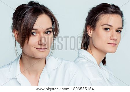 Studio portrait of young female twins sisters on gray