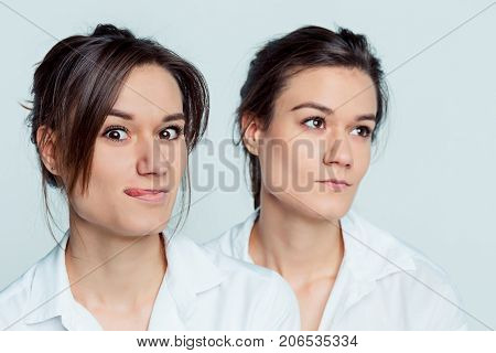 Studio portrait of young female twins sisters on gray