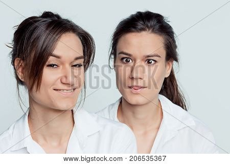 Studio portrait of young female twins sisters on gray
