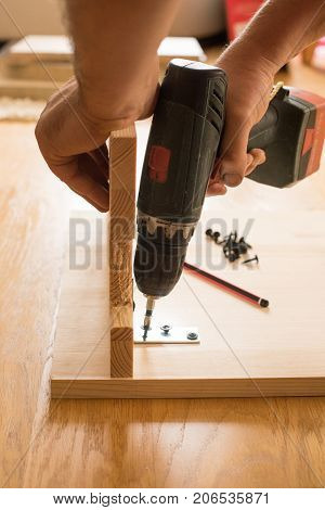 Cordless screwdriver holding by hand. Construction worker holding the hand drill. Screwdriver in the hand of the master. Carpenter working with an electric screwdriver  using a cordless screwdriver
