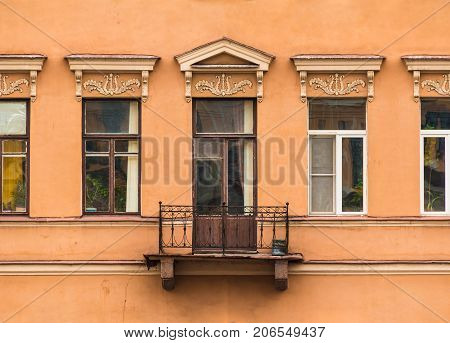 Several windows in a row and balcony on facade of urban apartment building front view St. Petersburg Russia