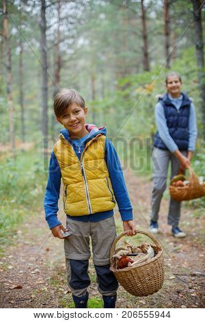 Mushrooms picking, season for mushrooms - lovely boy with his sister with picked fresh edible mushrooms in basket in the forest