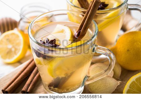Hot Ginger tea in glass mug with lemon honey and spices at white. Healing tea. Clise up.