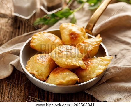 Baked dumplings stuffed with curd cheese and potatoes in a pan on wooden rustic table, nutritious and delicious vegetarian food,  Traditional Polish dish