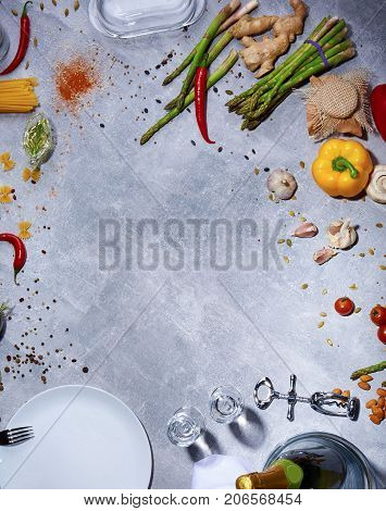 Top view of red chili pepper, cloves of garlic, mushrooms, salad pepper, corkscrew, white plate, seasonings, ginger, tomatoes, cucumbers on a light gray background.