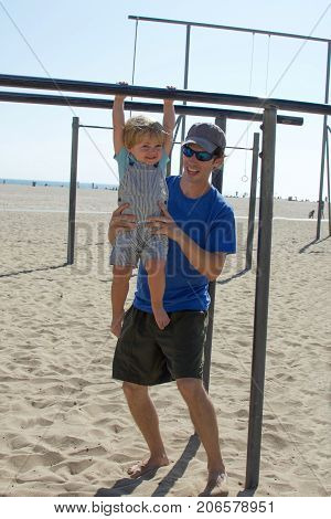 father and son playing together on park outside at beach