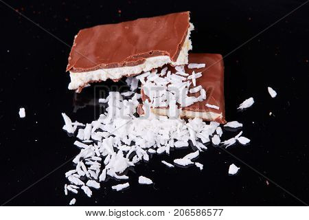 Homemade chocolate coconut bars with coconut flakes on top.