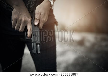 Robber holding gun for ready to murder steal moneys at abandoned building. Selective focus. criminality and social issues concept. Dark and low key tone tone pinterest and instragram like process.