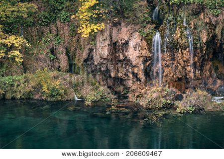  waterfall flows into the emerald lake surrounded by autumn forest popular tourist destination in Croatia. Nature background suitable for wallpaper.