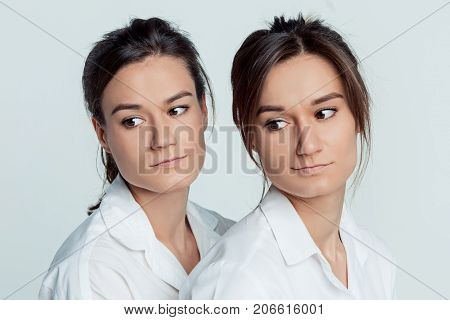 Studio portrait of young female twins sisters on gray