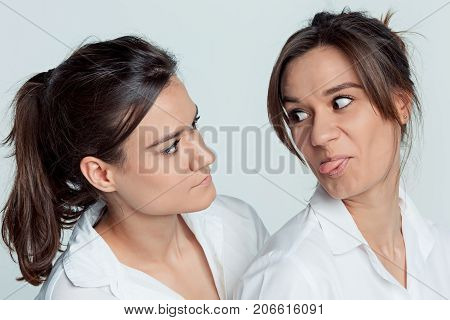 Studio portrait of young female twins sisters on gray