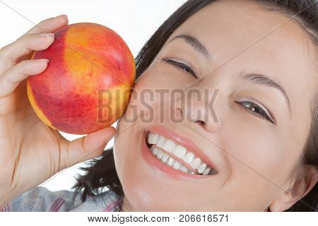 Perfect Skin Concept. Beautiful Girl Holding a Peach Near Her Face on a white background