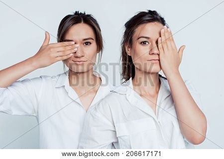 Studio portrait of young female twins sisters on gray