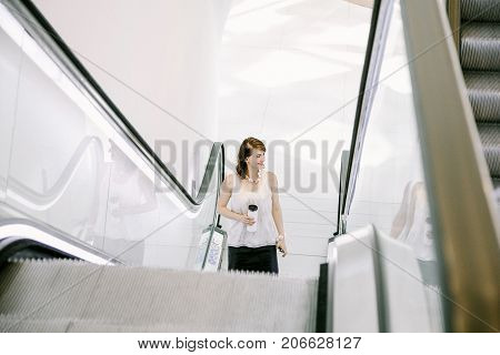Escalator In The Business Center. Business Woman With Coffee