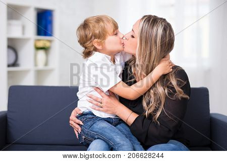 Family Portrait - Young Mother Kissing Her Cute Little Son At Home