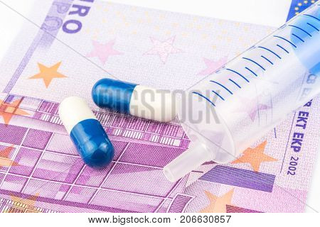 Two Small Pills And One Injection Are Laying On 500 Euro Banknote