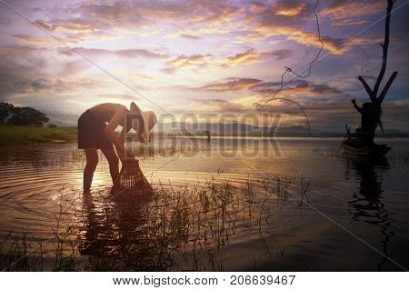 Asian young fisherman casting freshwater fish in nature river in the early morning before sunrise.