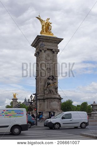 Paris; France- May 01; 2017: Golden Renommee du Commerce- statue on the Pont Alexandre III bridge by Pierre Granet on the socle counterweight on the bridge of Alexander III which was inaugurated in 1900.Nearby cars and people moving