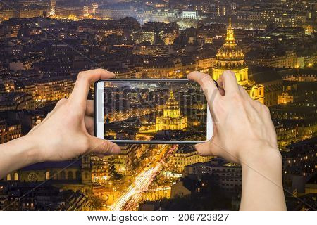 Tourist taking photo of Paris cityscape view at night with mobile smartphone.