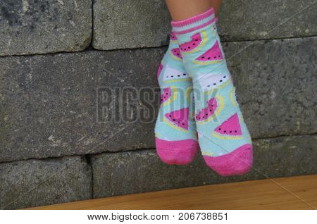 Girl feet in bright funny socks against a brick wall