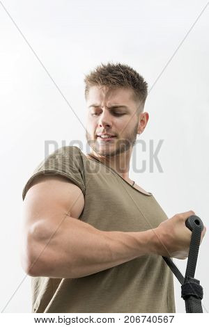 Young Man Winces And Stares At Bicep While Working Out