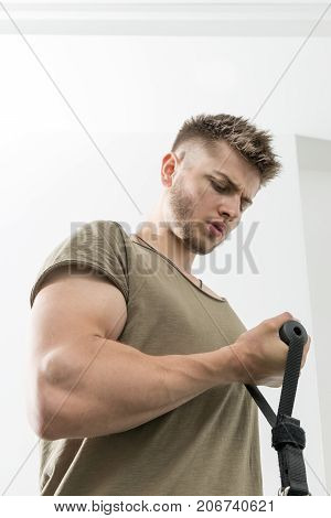 Young man doing bicep curls with cable machine in gym