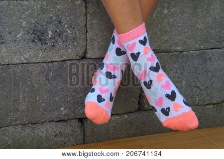 Girl feet in bright socks against a brick wall background