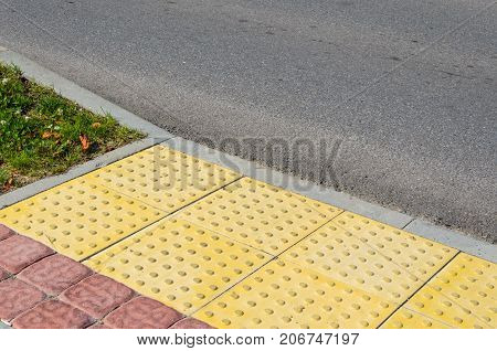 Adjoining Pavement with a Tactile Tile for Blind Peoples and an Asphalt Road. Joint of Road Surfaces