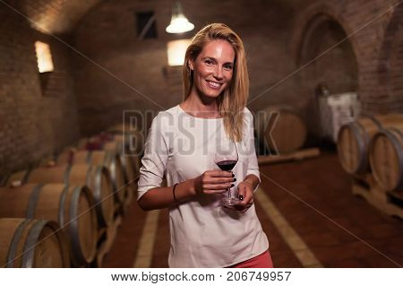 Beautiful woman oenologist tasting wine in winegrower cellar