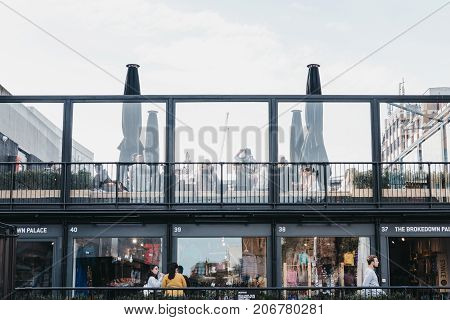 LONDON, UK - SEPTEMBER 24, 2017: People walking past and sitting at the roof cafe at BOXPARK Shoreditch, shipping container, pop-up mall for independent and fashion and lifestyle stores and cafes.