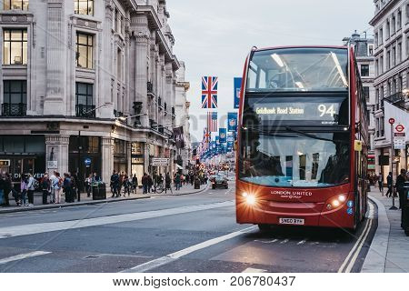 LONDON, UK - SEPTEMBER 24, 2017: Red double-decker bus on Regent Street, London. The street is decorated with NFL flags to celebrate the event and four NFL games played in capital in 2017.