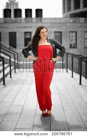 Beautiful overweight woman in red pantsuit standing on city street
