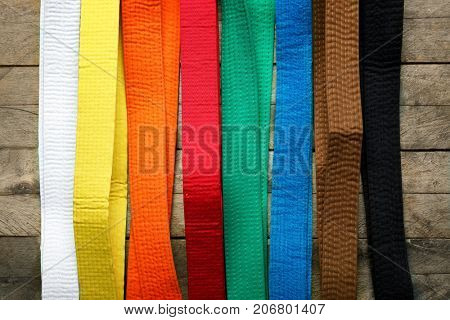 Colorful karate belts on wooden background