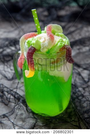 Green drink with ice cream float and gummy worms for Halloween party