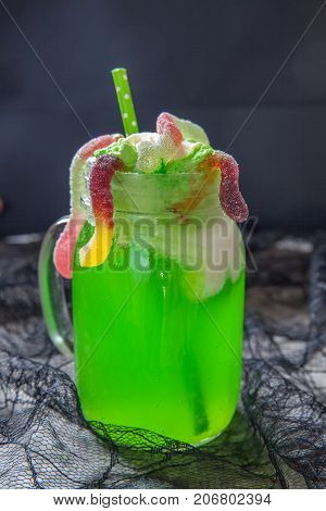 Green drink with ice cream float and gummy worms for Halloween party