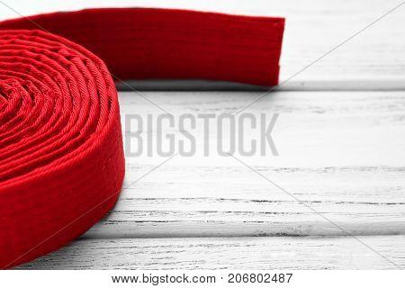 Red karate belt on wooden background